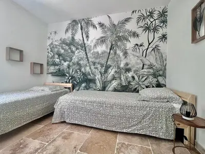 a bedroom with two beds and a mural of palm trees at Maison du Ventoux in Mormoiron