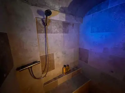 a large green bath tub in a room with a stone wall at Les Caves d 'Oía in Aix-en-Provence