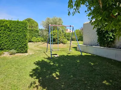 a swing set in a yard next to a hedge at Chez Cathy in Pernes-les-Fontaines