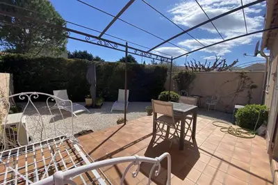 a patio with a table and chairs under a pergola at At Tinou's spacious quiet house with garden for 2 people in LʼIsle-sur-la-Sorgue