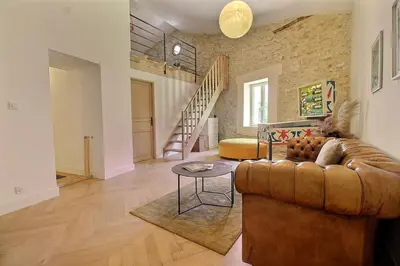 a living room with a leather couch and a table at Le Mas Rose Thé in Robion en Luberon