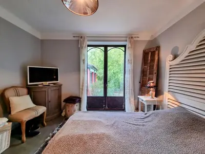a bedroom with a bed and a tv and a window at La Verrière des Songes in Robion en Luberon