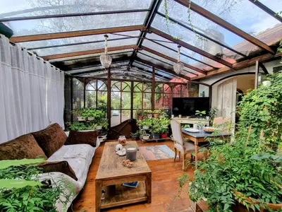 a conservatory with a couch and a table and some plants at La Verrière des Songes in Robion en Luberon