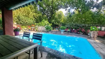 a swimming pool with chairs and a table at La Verrière des Songes in Robion en Luberon