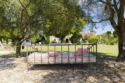 a bed sitting under a tree in a yard at Domaine Manon en Luberon privatisé - 22 couchages in Lagnes