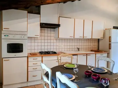 a kitchen with a table with chairs and white cabinets at Gîte Sorgue - Exceptionnel 125 m2 Piscine Parking Jardin in Saumane-de-Vaucluse