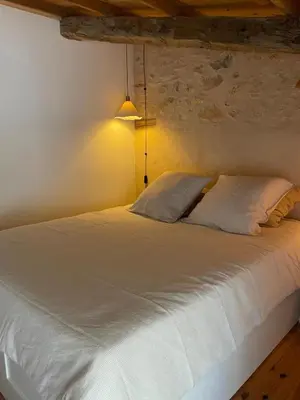 a bedroom with a large white bed with a lamp at 15 rue des pierres seches in Ferrassières
