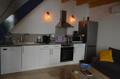 a kitchen with white cabinets and a couch at Maison en coeur de ville in LʼIsle-sur-la-Sorgue