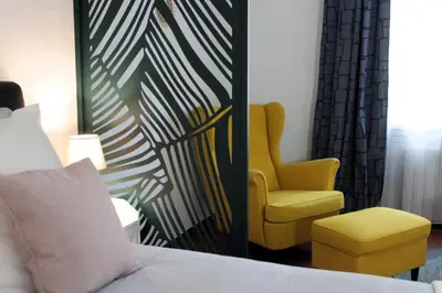 a bedroom with a bed and a yellow chair at Appartement Centre Historique in LʼIsle-sur-la-Sorgue