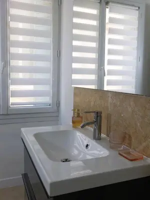 a white sink in a bathroom with two windows at Appartement Centre Historique in LʼIsle-sur-la-Sorgue