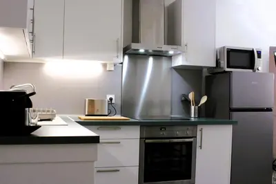 a kitchen with white cabinets and a refrigerator at Appartement Centre Historique in LʼIsle-sur-la-Sorgue