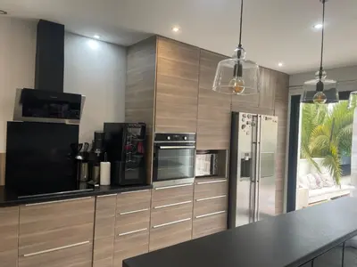 a kitchen with wooden cabinets and a black counter top at Villa entière piscine jacuzzi venelles in Venelles