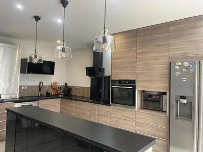 a kitchen with stainless steel appliances and wooden cabinets at Villa entière piscine jacuzzi venelles in Venelles