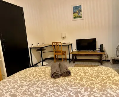 a bedroom with a bed with a desk and a chair at Studio Rdc proche Quai Rouget in LʼIsle-sur-la-Sorgue