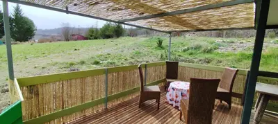 a table and chairs on a deck with a view of a field at Chalets dans le Luberon in Viens