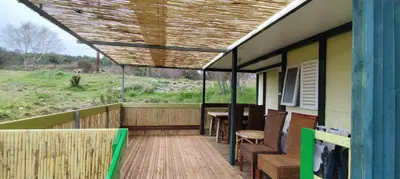 a porch with a roof with a table and chairs at Chalets dans le Luberon in Viens