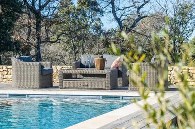 a patio with wicker furniture next to a swimming pool at La Villa des Cedres in Bonnieux