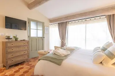 a bedroom with a large bed with a dresser and window at La Villa des Cedres in Bonnieux