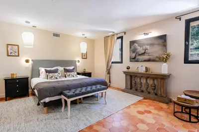 a bedroom with a bed and a bench in it at La Villa des Cedres in Bonnieux