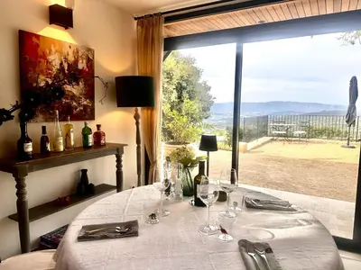a dining room with a table and a large window at La Villa des Cedres in Bonnieux