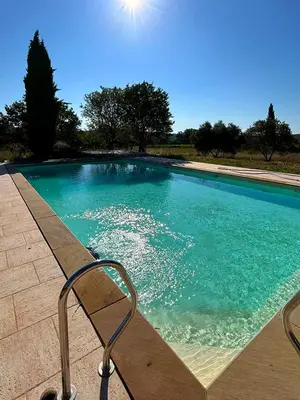 a swimming pool with a chair sitting next to it at Authentique mas provençal avec piscine in Beaumont-de-Pertuis