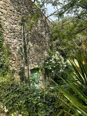 a stone building with a window in a garden at Authentique mas provençal avec piscine in Beaumont-de-Pertuis