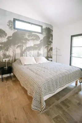 a bedroom with a bed with a tree mural on the wall at The Aviary - Pernes-les-Fontaines in Pernes-les-Fontaines