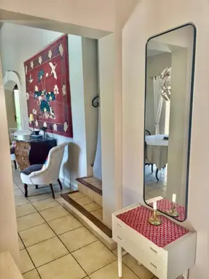 a living room with a mirror and a table at La Maison Rose in LʼIsle-sur-la-Sorgue