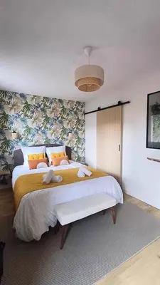 a bedroom with a large bed with yellow and orange pillows at Le Colibri - studio paisible et raffiné au sud d'Aix in Aix-en-Provence