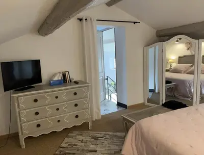 a bedroom with a dresser with a television on it at Mas provençal au coeur de L'Isle-sur-la-Sorgue in LʼIsle-sur-la-Sorgue