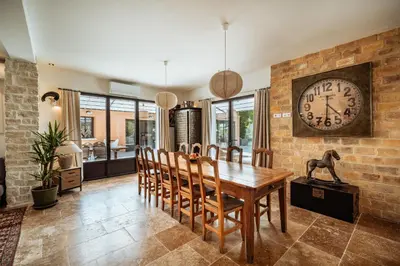 a dining room with a table and a clock on the wall at La Source Blanche in Gargas