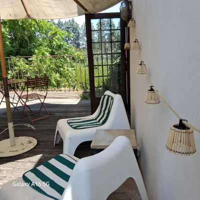a porch with two chairs and a table and an umbrella at gîtes carita in Cabannes