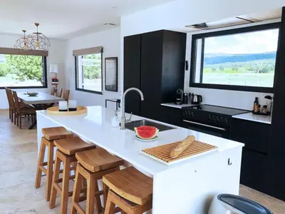 a kitchen with a large white counter and wooden stools at Villa with pool in Provence bij de Mont Ventoux in Blauvac