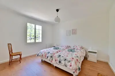 a white bedroom with a bed and a chair at Villa Marie-Rose in Saint-Didier
