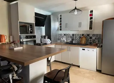 a kitchen with white cabinets and a wooden table at Mas Bourbon in Cavaillon