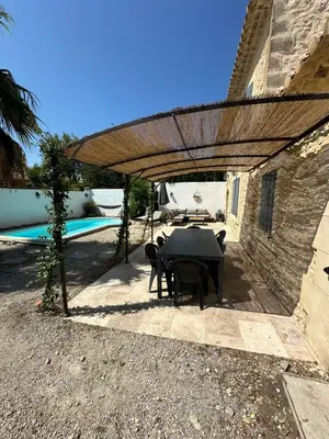a patio with a table and chairs under a wooden umbrella at Mas Bourbon in Cavaillon