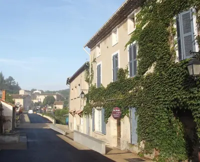 a building covered in ivy next to a street at Chambres et table d'hôtes Au Brabo in Mormoiron