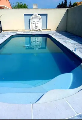 a blue swimming pool with a statue of a head at villa zen en provence in Velleron