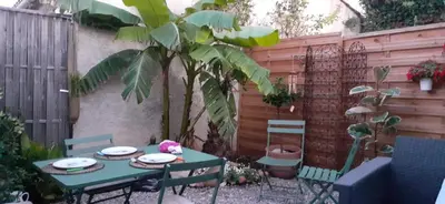 a table and chairs in a garden with a palm tree at Ty'ca house in Velleron
