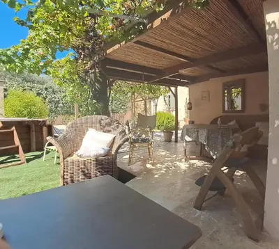 a patio with wicker chairs and a wooden pergola at Tramontane chambre salon et piscine in Jonquerettes