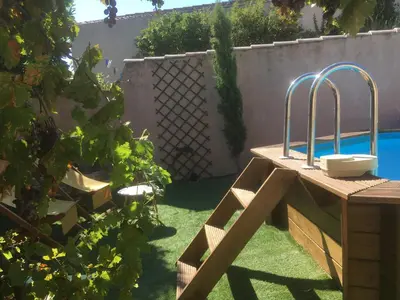 a garden with a wooden table and a swimming pool at Tramontane chambre salon et piscine in Jonquerettes