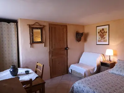 a bedroom with two beds and a table and a door at Chambre d'hôte dans ferme provençale in Banon