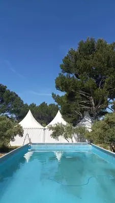 a swimming pool with white tents in the background at La Cayon Au coeur des oliviers en Provence in Pélissanne