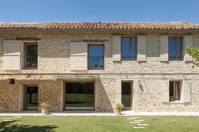 a stone building with windows and a yard at Mas spacieux Les Agasses calme - Isle sur sorgue in LʼIsle-sur-la-Sorgue