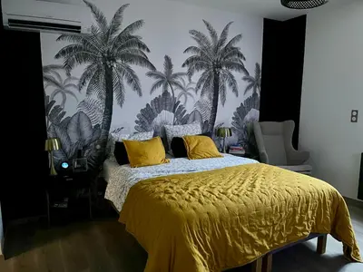 a bedroom with a yellow bed with palm trees on the wall at Le Mas des platanes-piscine-gîte-Clim-parking in Monteux