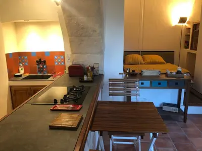 a kitchen with a counter with a stove and a bed at studio au coeur de Lacoste in Lacoste