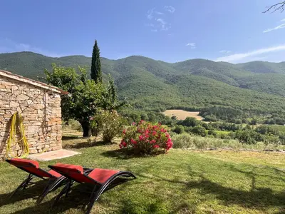 two red chairs sitting in the grass next to a building at Le Grand Hermas in Saint-Martin-de-Castillon