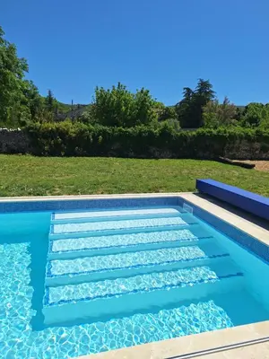 a swimming pool in a backyard with a lawn at Le Portail Vert in Villes-sur-Auzon