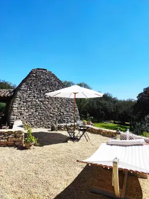an umbrella and two chairs in front of a stone building at Le Mas Natán in Gordes