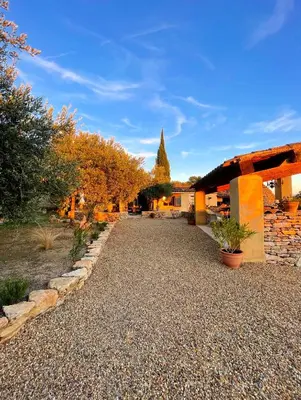 a gravel driveway with trees and a building at Le Mas Natán in Gordes